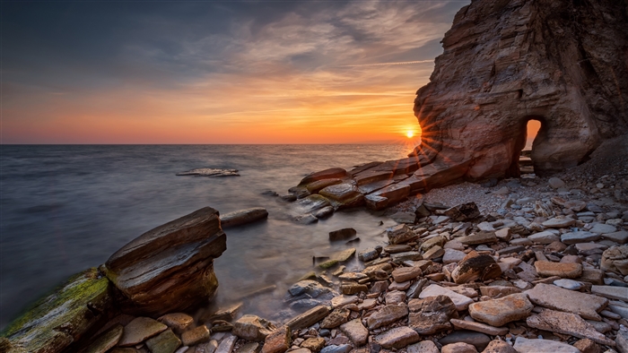 Sunrise over rocky coast with sea arch