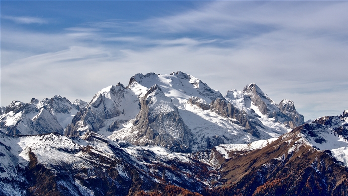 Snow-capped mountains under a blue sky with clouds