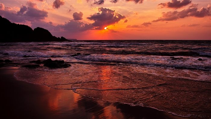 Sunset over the ocean with a rocky beach