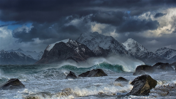 Waves crashing on rocks with snowy mountains in Lofoten Islands, Norway 4K