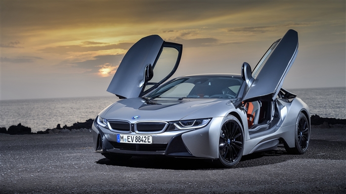 Silver BMW i8 with butterfly doors open at sunset