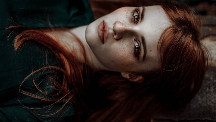 Redhead woman with freckles lying down