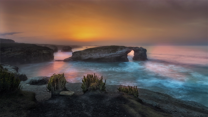 Ocean arch rock formation at sunset 4K