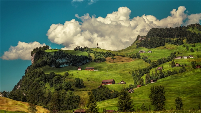 Green hills with houses and a church under a cloudy sky