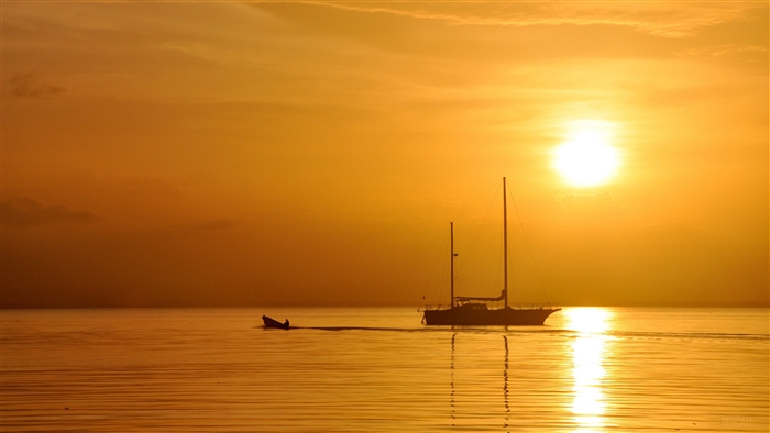Sailboat and dinghy at sunset over the ocean