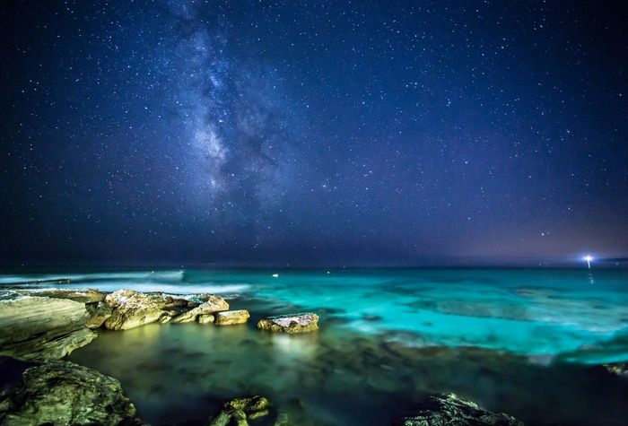 Milky Way over the ocean and rocks at night