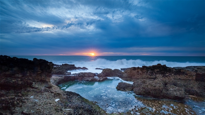 Sunset over rocky coast with ocean waves