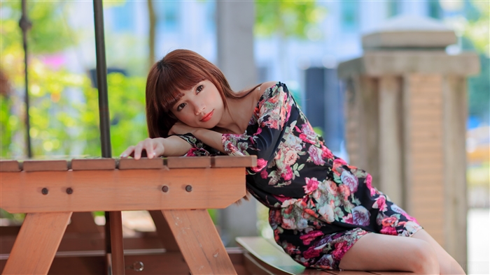Woman in floral dress resting on a picnic table