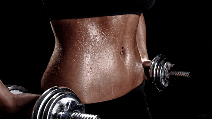 Woman with toned abs holding dumbbells