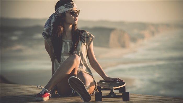 Woman with Skateboard on Wooden Boardwalk by the Ocean