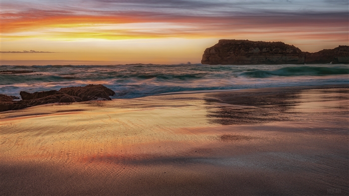 Beach with ocean waves and rock formations at sunset 4K