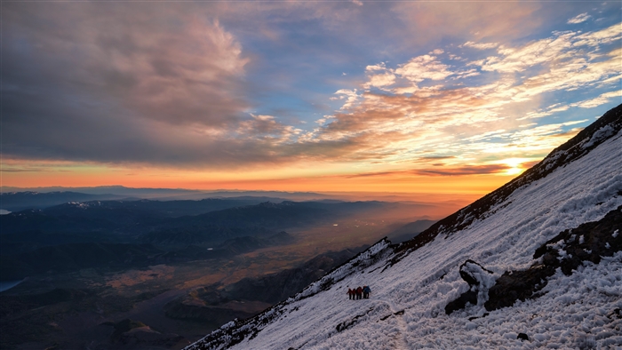 Hikers on a snowy mountain slope at sunrise