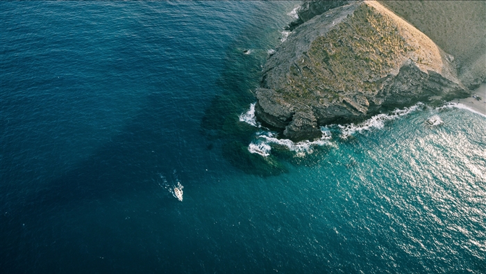 Aerial view of a sailboat near a rocky coastline