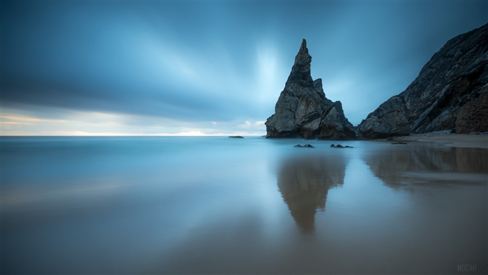 Tall rock formation in the ocean at dusk