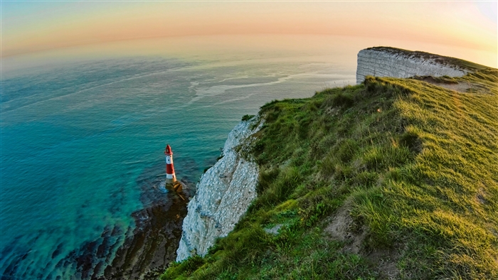 Lighthouse on a cliff overlooking the ocean at sunset