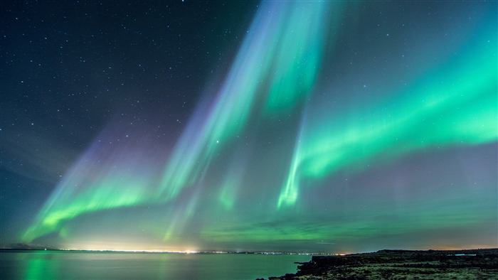Aurora Borealis over the ocean and land