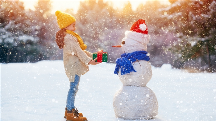 Child Giving Gift to Snowman in Snowfall Winter Scene