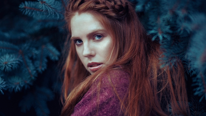 Redhead woman with blue eyes in purple outfit near pine tree