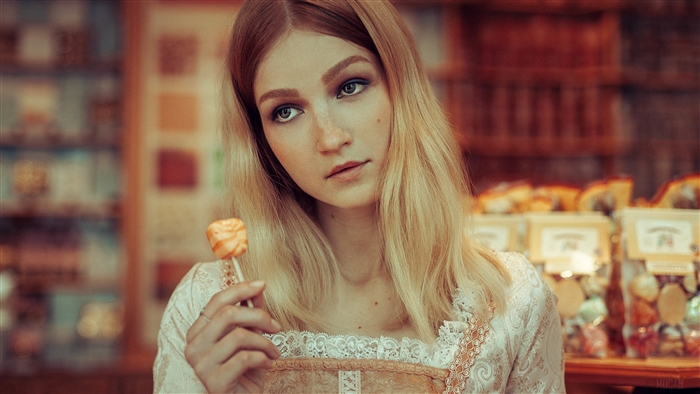Blonde woman holding candy pop in candy store 4K