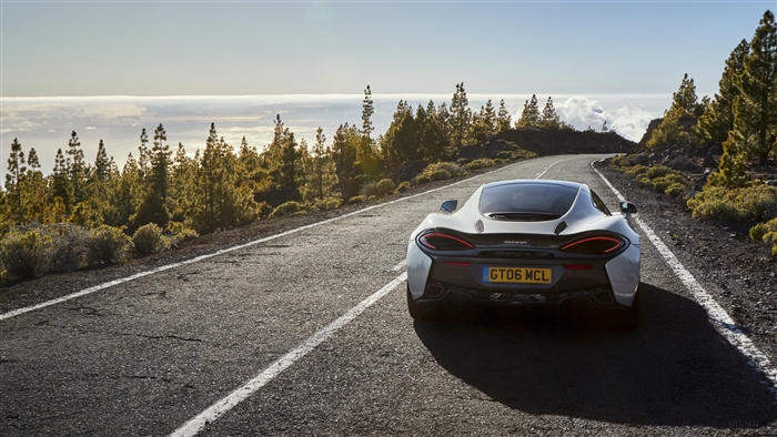 White McLaren 570GT driving on a mountain road