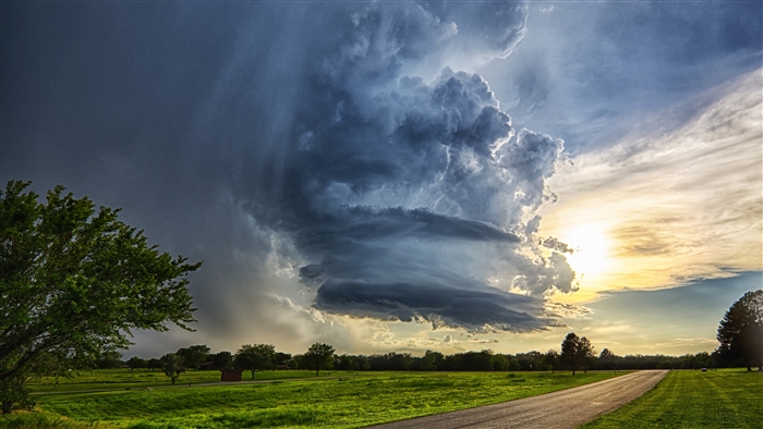 Dramatic Cloud Formation Over Sunlit Road