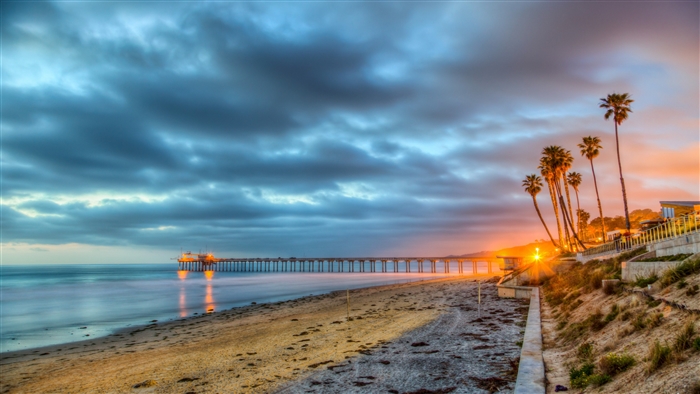 Beach pier at sunset with palm trees