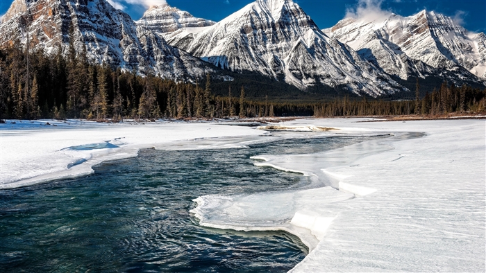Snow-covered mountains and a partially frozen river in Alberta, Canada 4K