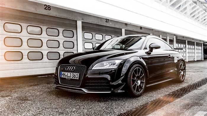 Black Audi TT RS parked in front of garage bays