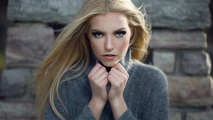 Woman with blonde hair and green eyes wearing a grey sweater