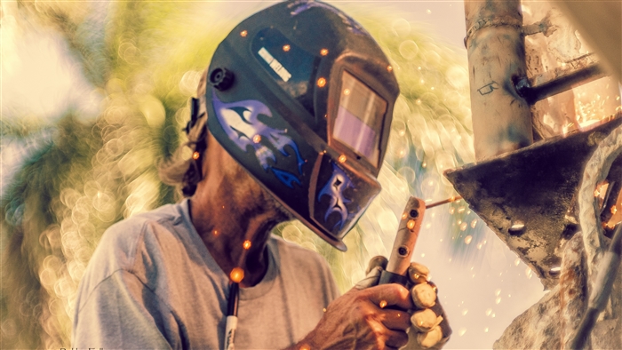 Welder wearing a helmet with flames, sparks flying