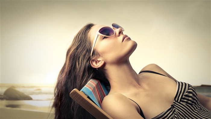 Woman in sunglasses sunbathing on a beach