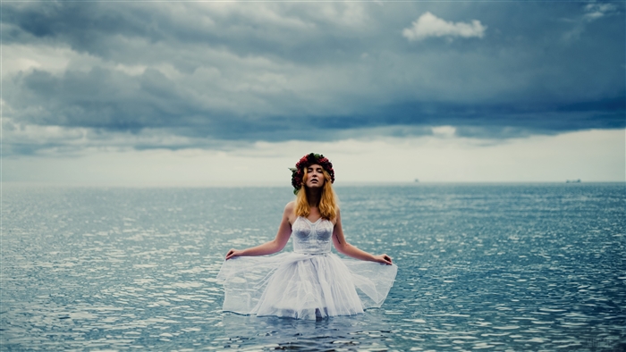 Woman in white dress with flower crown in water