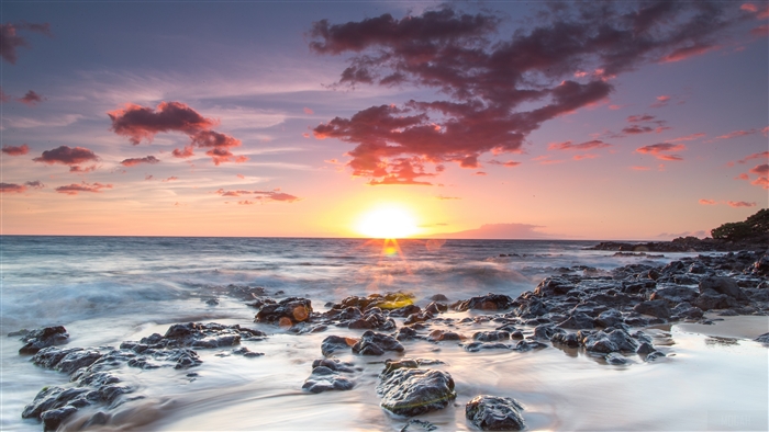 Sunset over the ocean with rocky shore