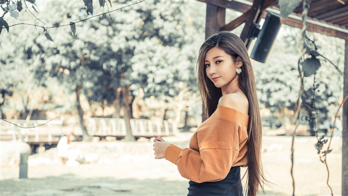 Woman in orange off-the-shoulder sweater outdoors