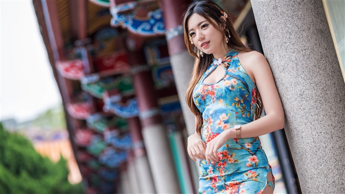 Woman in a floral dress leaning on a pillar