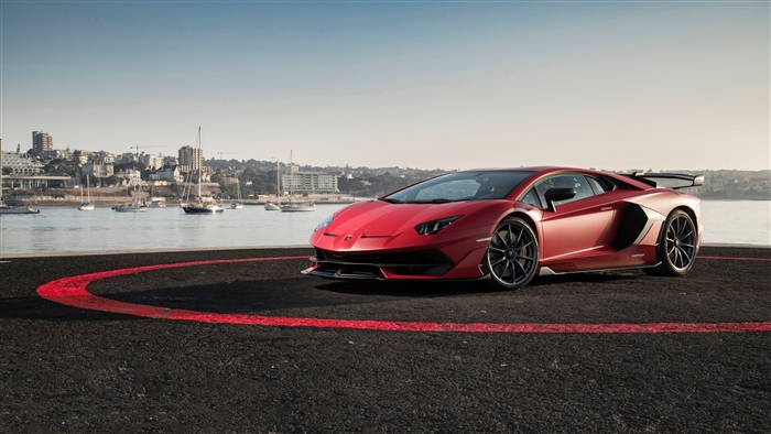 Red Lamborghini Aventador SVJ on helipad with city and boats