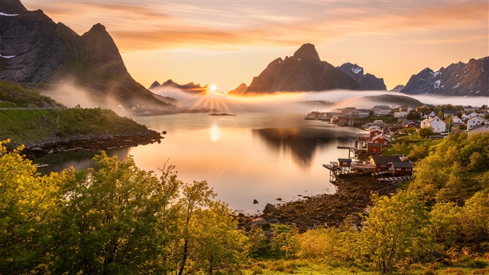 Village by a lake at sunrise with mountains