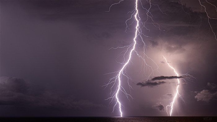 Lightning strikes over the ocean at night
