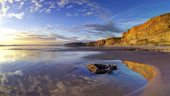 Beach cliff and ocean reflection at sunset