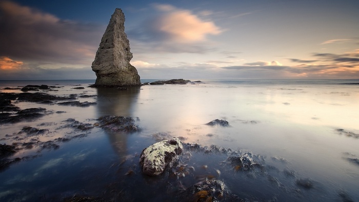 Tall rock formation in the sea at sunset