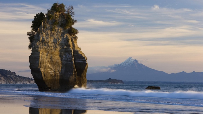 Rock formation and Mount Taranaki at sunset