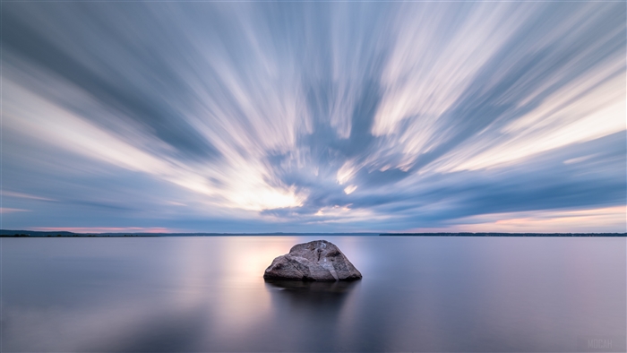 Long Exposure of Rock in Calm Lake Under Streaky Clouds