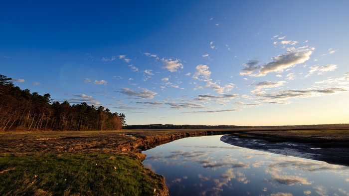 River reflecting clouds and trees under a blue sky