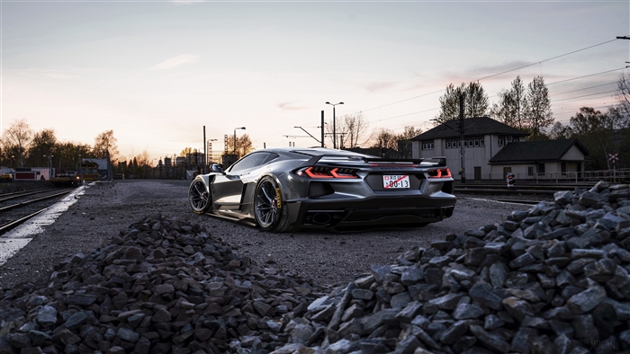 Gray Corvette C8 parked on gravel near train tracks