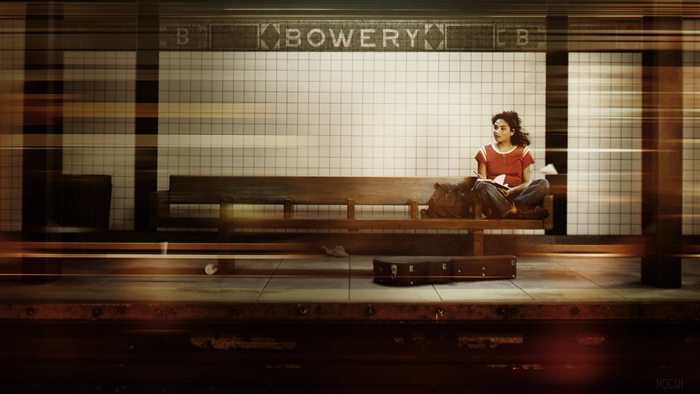 A woman sits on a bench at the Bowery subway station