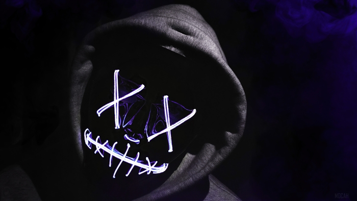 Person in a Purge mask wearing a hoodie