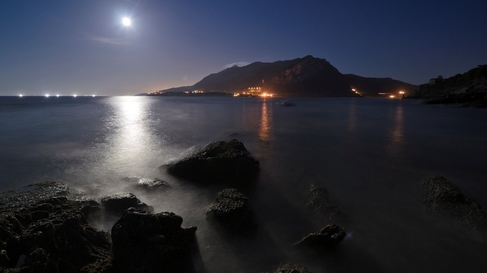 Moonlit Coastline with Distant Lights and Mountains