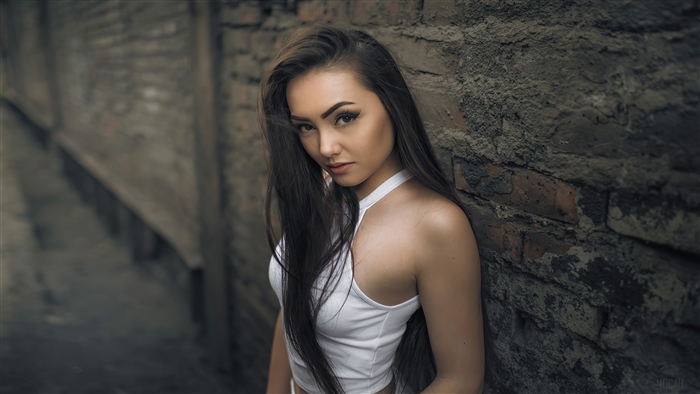 Woman leaning against a brick wall