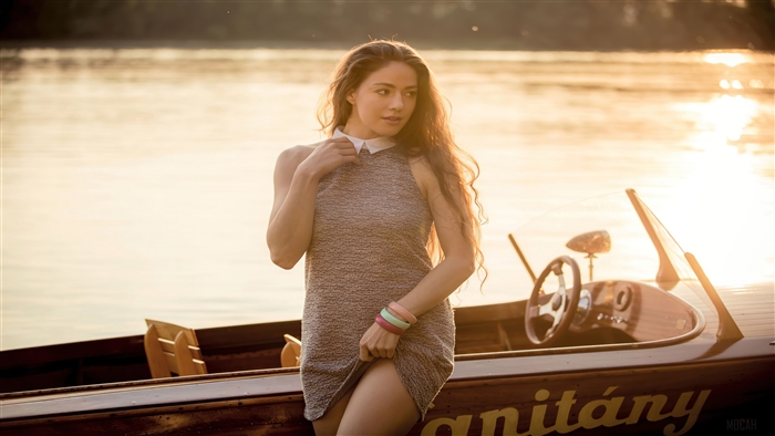 Woman in dress posing by a boat