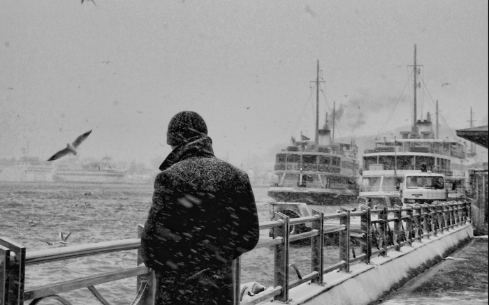 Man watching ferries in a snowstorm